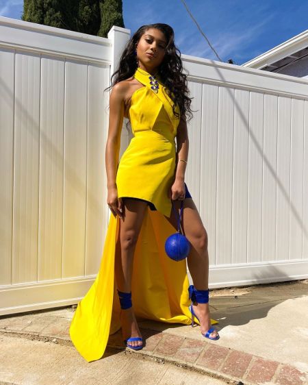 Sierra Capri in a yellow dress poses for a picture.